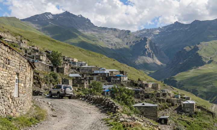 Stone houses of a high Caucasus village above a winding mountain road Stone houses of a high Caucasus village above a winding mountain road