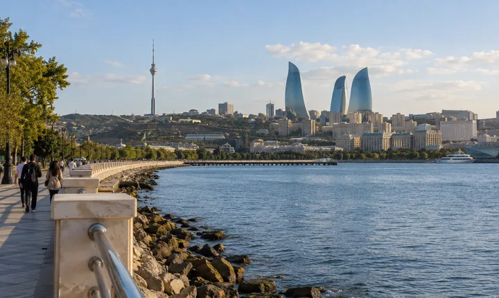 Walkers beside the Caspian waterfront with Baku skyline in the distance Walkers beside the Caspian waterfront with Baku skyline in the distance