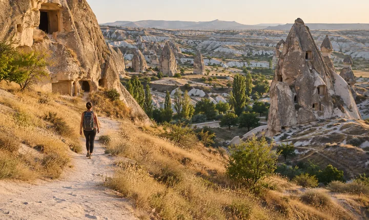 A hiker following a dusty path among Cappadocia rock formations
