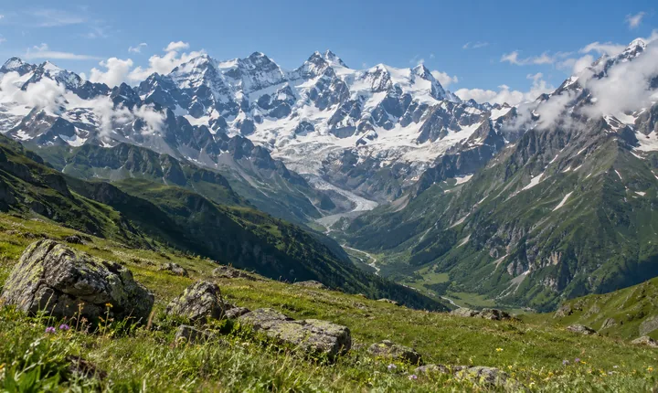 Snow-covered Caucasus peaks and a glacier above a summer alpine meadow Snow-covered Caucasus peaks and a glacier above a summer alpine meadow