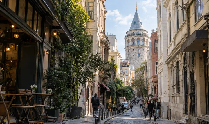 Pedestrians on a cobbled street below Galata Tower in Istanbul