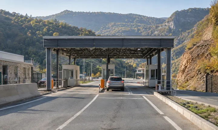 A car approaching a small vehicle border checkpoint in the wooded South Caucasus A car approaching a small vehicle border checkpoint in the wooded South Caucasus