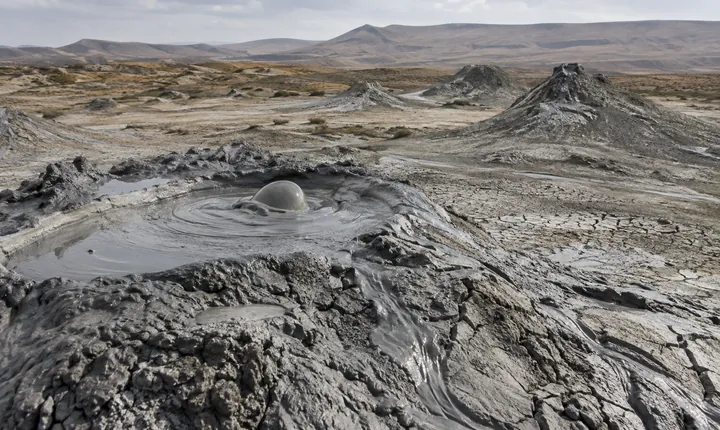 A small bubbling mud vent and low cones in an arid Gobustan landscape A small bubbling mud vent and low cones in an arid Gobustan landscape