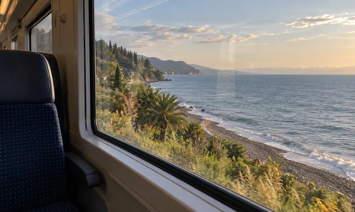 An empty train window seat overlooks the Black Sea and a pebbled Georgian shoreline An empty train window seat overlooks the Black Sea and a pebbled Georgian shoreline