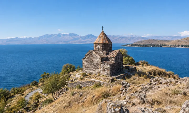 Sevanavank monastery above the blue water of Lake Sevan and its surrounding mountain rim Sevanavank monastery above the blue water of Lake Sevan and its surrounding mountain rim