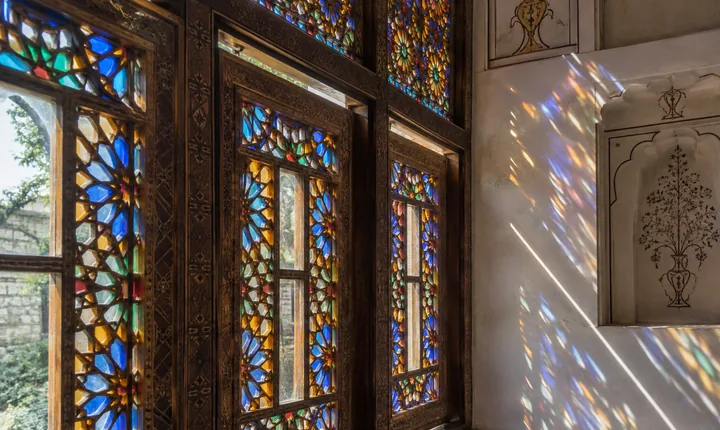 Geometric colored glass and carved timber in a traditional Sheki window Geometric colored glass and carved timber in a traditional Sheki window