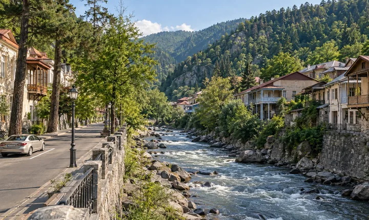 A parked sedan beside a riverside street and wooded valley in Borjomi A parked sedan beside a riverside street and wooded valley in Borjomi