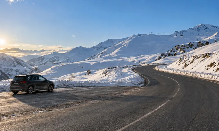 A parked SUV beside a cleared mountain road and snowy slopes near Gudauri A parked SUV beside a cleared mountain road and snowy slopes near Gudauri