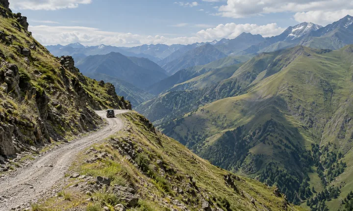 Gravel road across the Abano Pass toward Tusheti with a small 4x4 and green Caucasus slopes Gravel road across the Abano Pass toward Tusheti with a small 4x4 and green Caucasus slopes