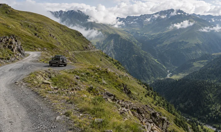 A gravel switchback winds across green slopes on Georgia's Abano Pass toward Tusheti A gravel switchback winds across green slopes on Georgia's Abano Pass toward Tusheti