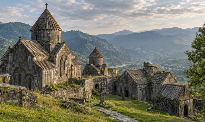 Ancient grey-stone churches with conical roofs in a grassy Armenian monastery courtyard Ancient grey-stone churches with conical roofs in a grassy Armenian monastery courtyard